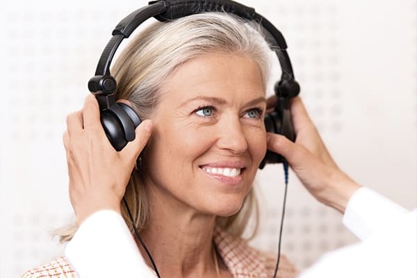 Ženska na sliki želi bolje slišati in si izboljšati sluh s pomočjo naprednih slušnih aparatov Neuroth